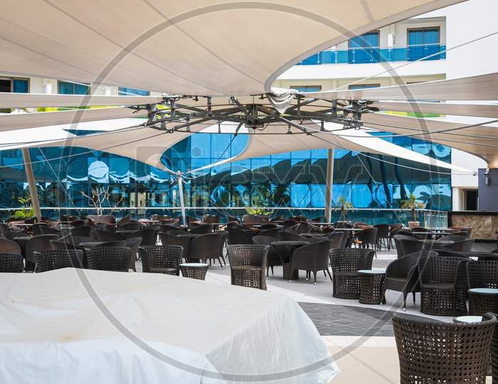 Huge Dining Area With Dark Tables And Chairs Outside Under Huge Umbrellas In The Hotel