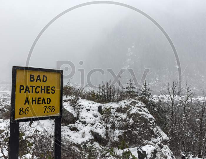 A Bad Patches Ahead Signboard Beside Road To Alert Drivers.