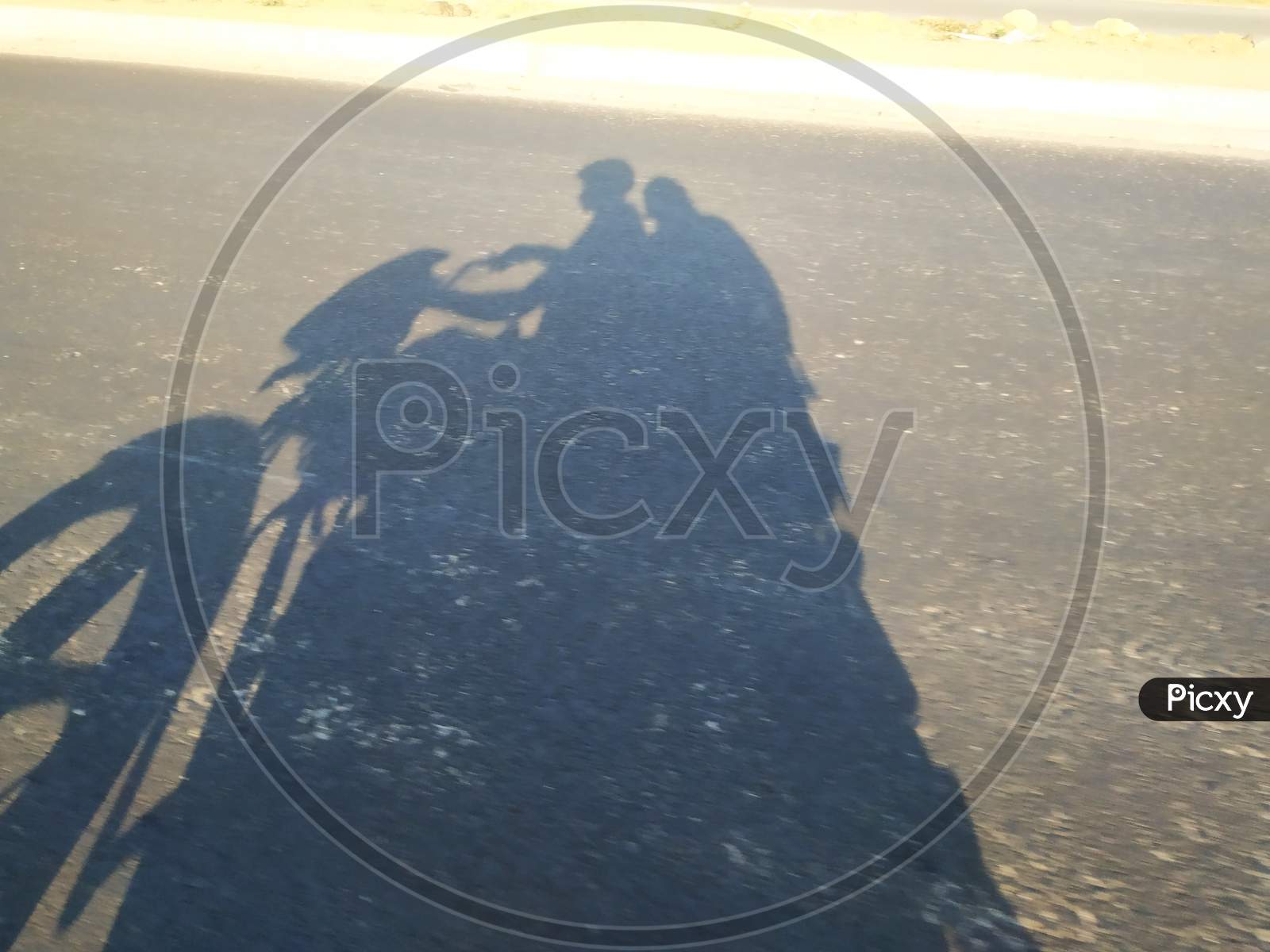 Closeup of shadow in a asphalt road men driving the bike and girl sitting back