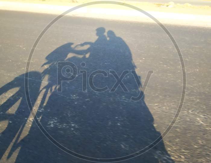 Closeup of shadow in a asphalt road men driving the bike and girl sitting back
