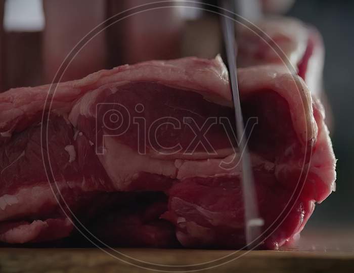 Closeup Shot of Butcher hand cutting meat on kitchen