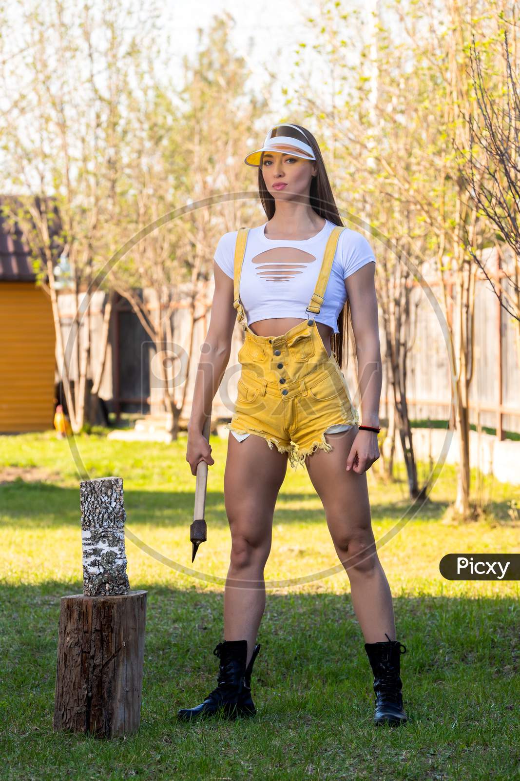 A Sportive Woman Lumberjack Cuts A Tree With A Big Ax. Bodybuilder With An Ax. Fitness Woman With Ax