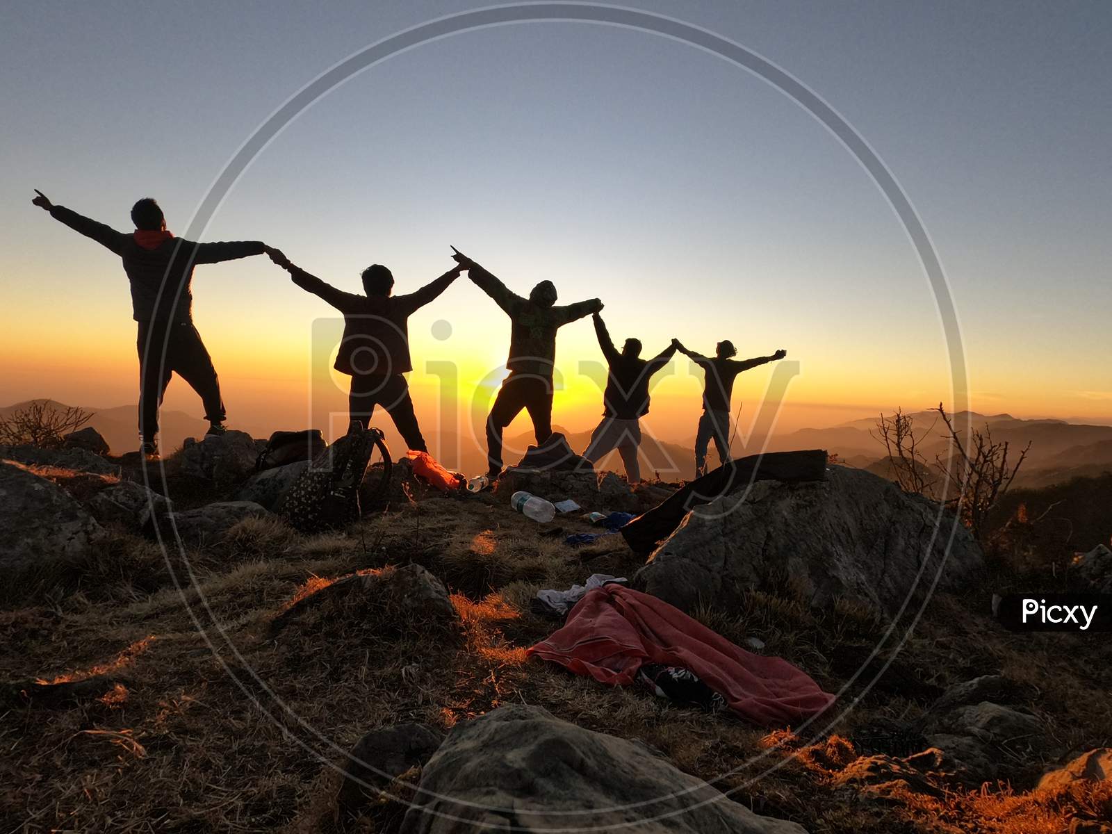 Four group of people standing together to create best shot of their journey in mountains  and guess what ? The perfect timing "Sun Set"