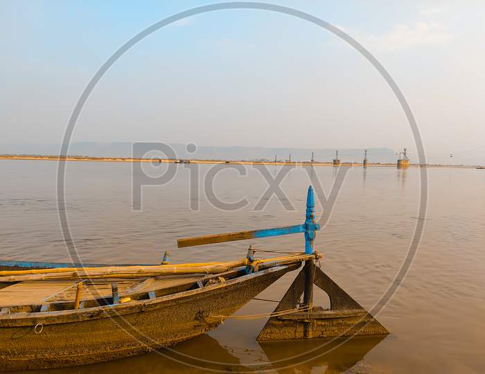 Boat In River With Light Yellow Blue Sky Background.