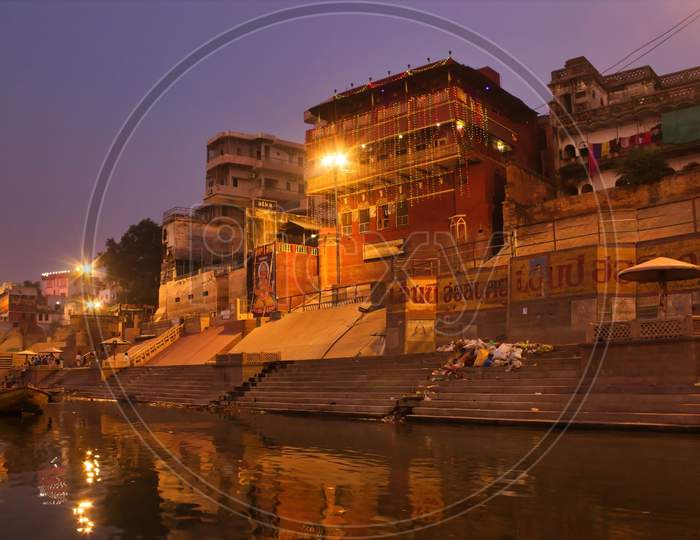 India, Varanasi Ganges River Ghat With Ancient City Architecture As Viewed From A Boat On The River At Morning Time.