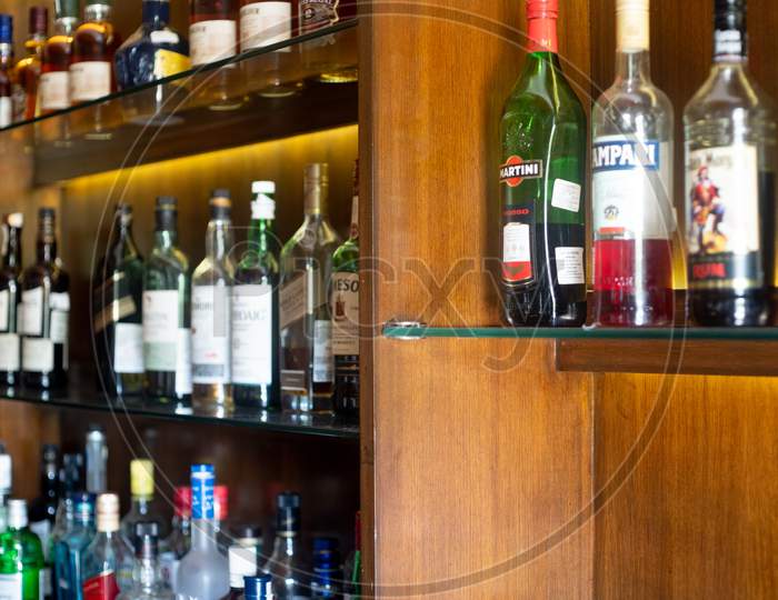 Soft Focus Shot Of Wooden Shelf In A Bar Pub Hotel Filled With Liqor Bottles From Top Brands Of Whiskey, Gin, Rum, Vodka And More