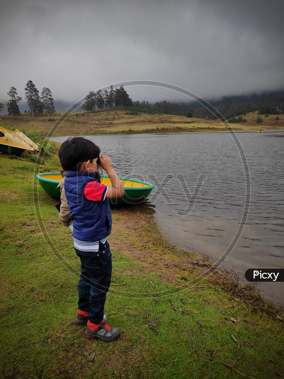 Boy Or Kid Or Chidren Standing On Shore Of Lake On Green Fileds Watching Beauty Of Lake And Boating In Kodaikanal,India. Tourism And Travel Concept Image, Fresh And Relax Type Nature Image