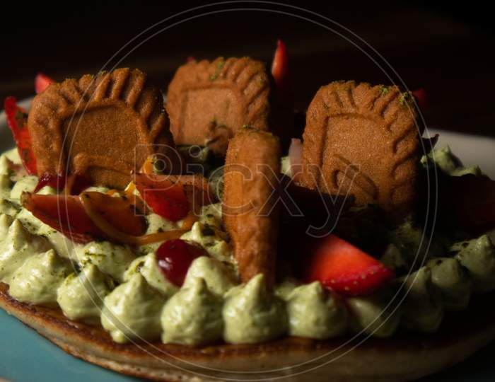 Avocado dessert with biscuits and pancake served on a white and blue plate