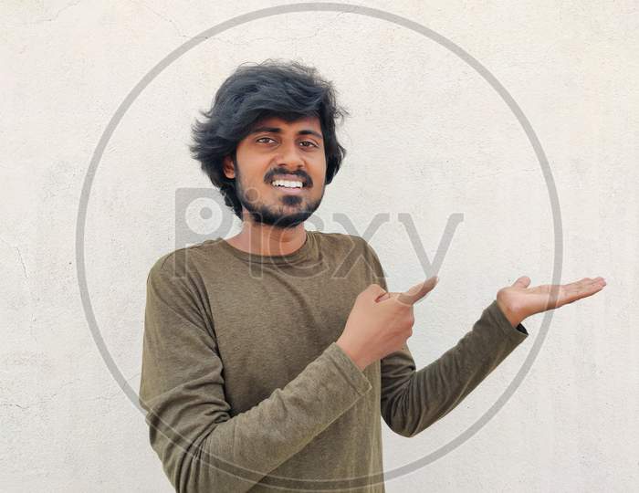 Super Excited Smiling Tamil Man Pointing Finger At Copy Space On His Palm. White Background