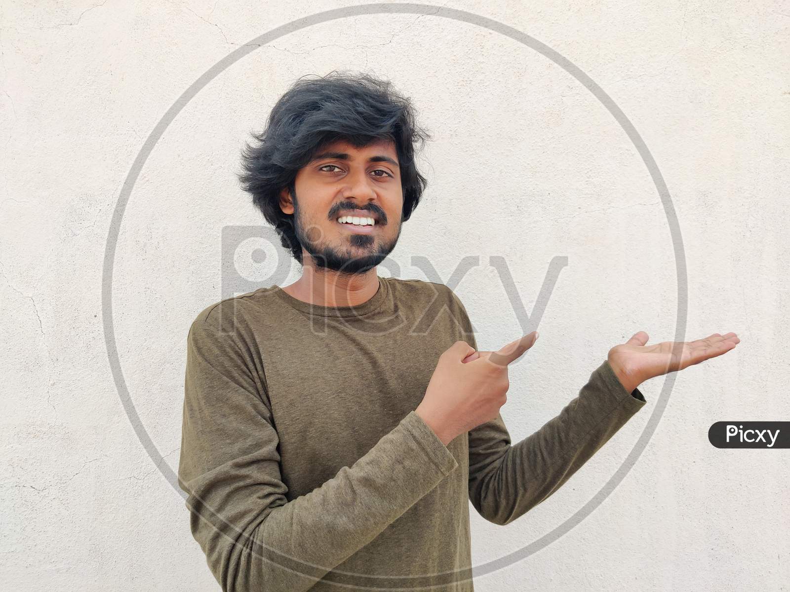 Super Excited Smiling Tamil Man Pointing Finger At Copy Space On His Palm. White Background
