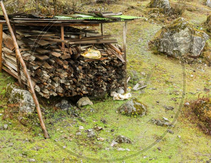 An Wooden Shade To Store Woods With Green Meadow In Background At Lachung Village Of North Sikkim.