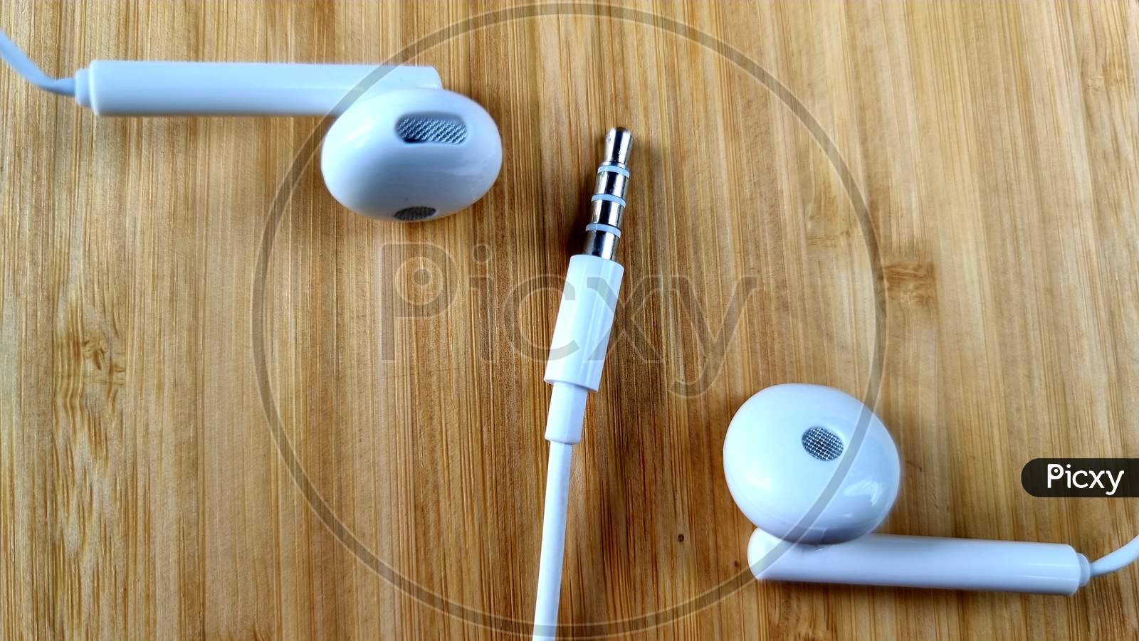 White Mobile headphones on wooden table, white headphones