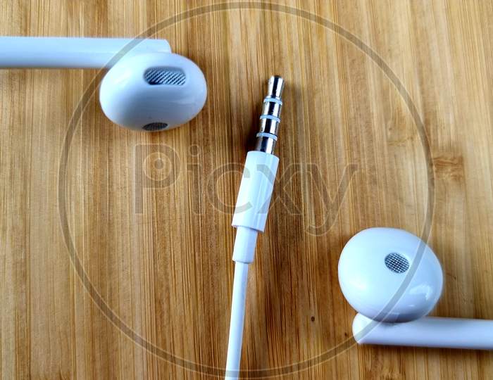 White Mobile headphones on wooden table, white headphones