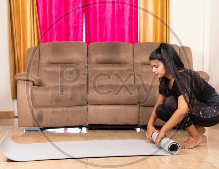 Young Girl Preparing Starting For Yoga At Home By Unfolding Mat On Floor - Concept Of Fitness, Workout And Healthy Life From Home During Coronavirus Or Covid-19 Pandemic.