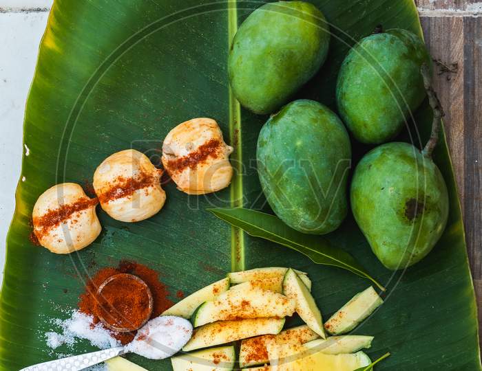 Fresh green mango and salt and red chilli on basket and old wooden floor background, group of raw mangoes with high vitamin C fruit for health.