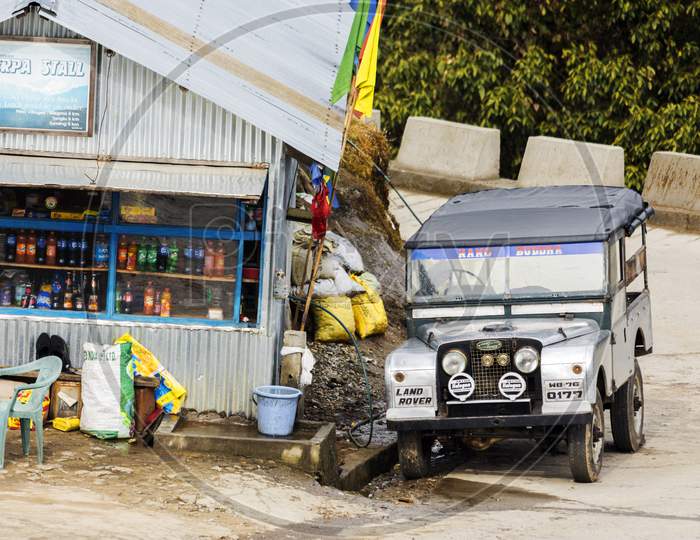 A Old Land Rover Car Parked Beside A Road Side Food Stall At Megma, West Bengal, India.