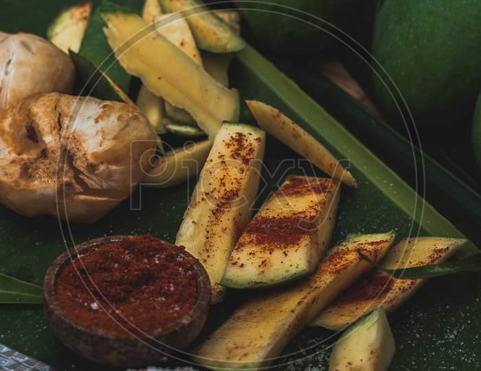 Fresh green mango and salt and red chilli on basket and old wooden floor background, group of raw mangoes with high vitamin C fruit for health.maggo