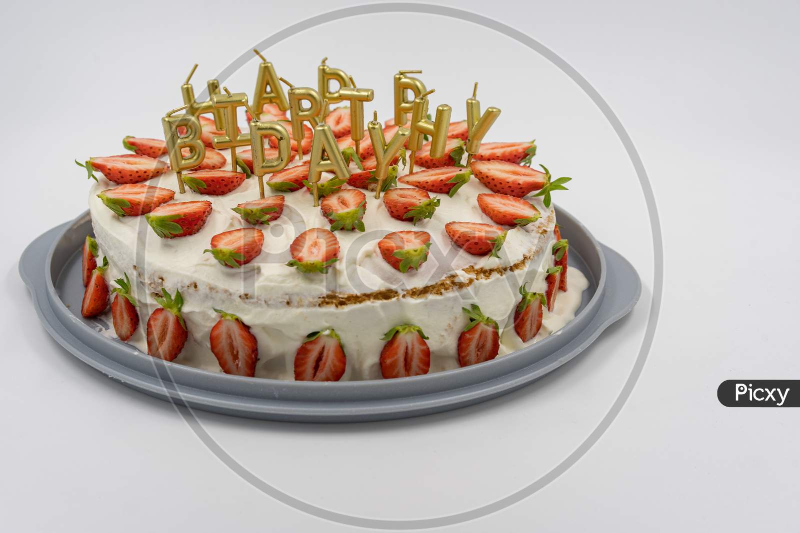 Isolated Strawberry Cheesecake On White Background Decorates With Golden Candles As Happy Birthday Letters.