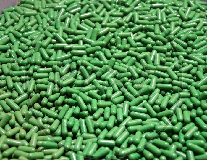 closeup of a lot of green capsules. A pile of tablets, pills, and capsules
