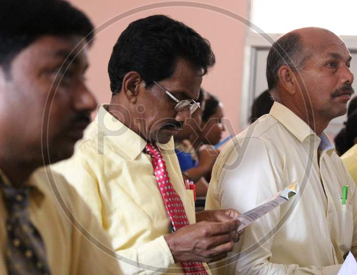 Attentive senior Indian  businessman holding documents focused on listening at group meeting,