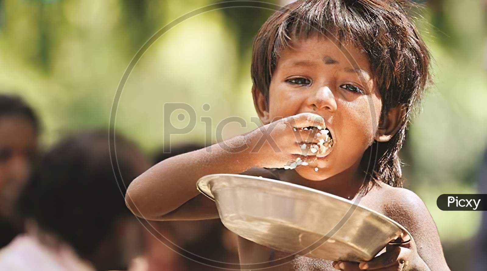Unidentified poor kid eating food in the street. Poverty in india.