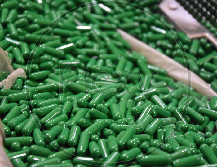 closeup of a lot of green capsules. A pile of tablets, pills, and capsules