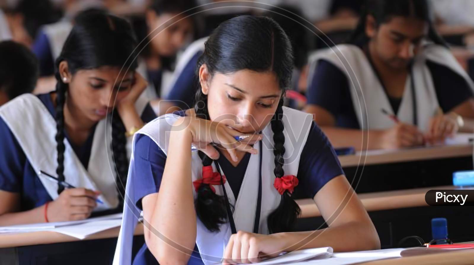Indian girl student concentrating in classroom. studying from notebook.