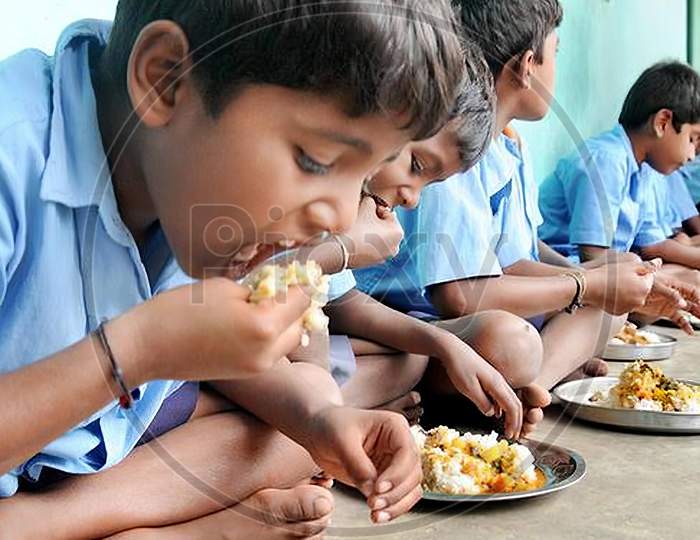 ndian school children sitting down and eating free mid day meal at a government school, Mid day meal