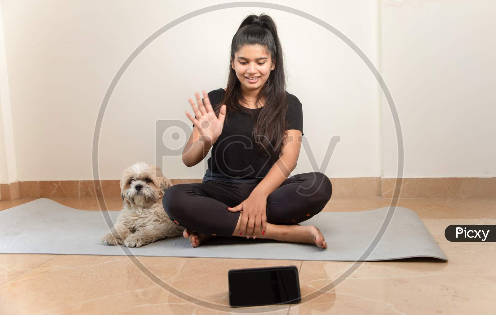 Girl Greeting On Online Class From Mobile Phone For Exercise - Concept Of Online Yoga Live Streaming On A Smartphone - Yoga Trainer Teaching Via Internet From Home.