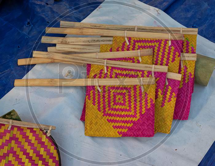 Beautiful Handmade Hand Fan Made By Bamboo Is Displayed In A Shop For Sale In Blurred Background. Indian Handicraft