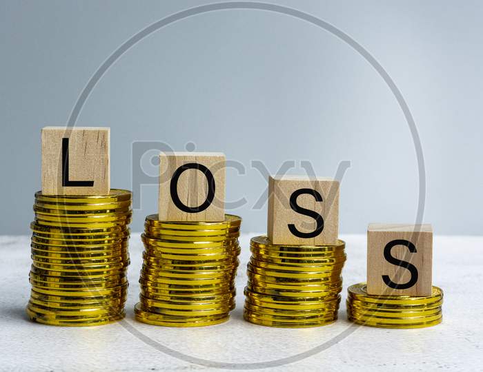 Loss Text On Wood Block With A Pile Of Coins