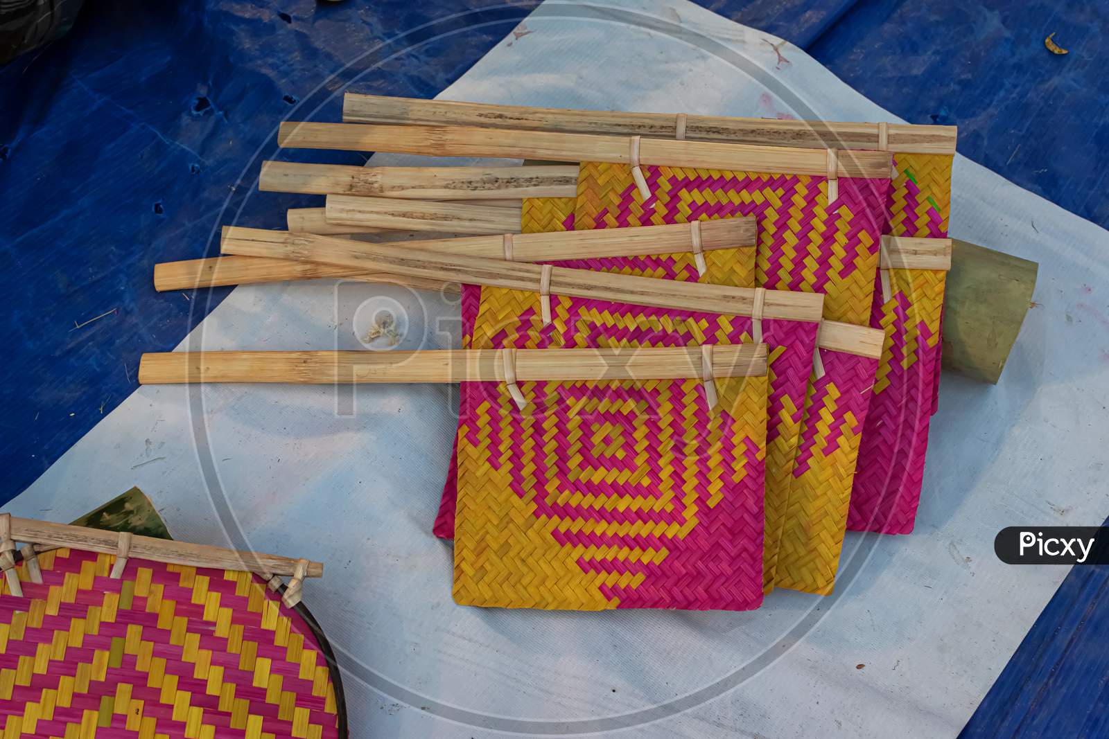 Beautiful Handmade Hand Fan Made By Bamboo Is Displayed In A Shop For Sale In Blurred Background. Indian Handicraft