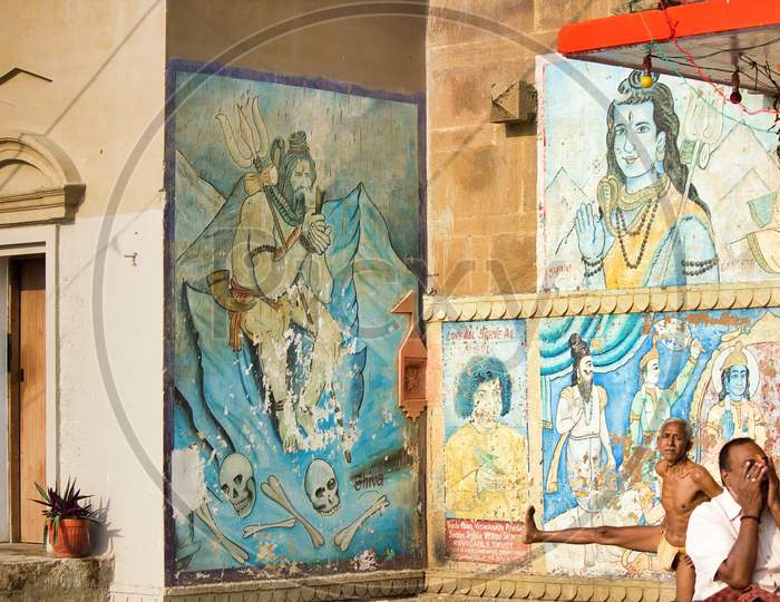 Varanasi, India - November 01, 2016: Wide Angle Shot Of People Doing Yoga During Morning Against Colorful Hindu God Such As Shiva And Rama Painting Or Graffiti On Wall In The State Of Uttar Pradesh