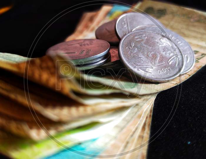 Indian paper currency with coins on isolated black background, concept of savings and investment