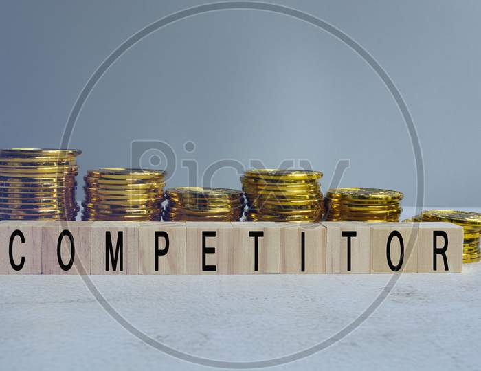 Competitor Text On Wood Block With A Pile Of Coins