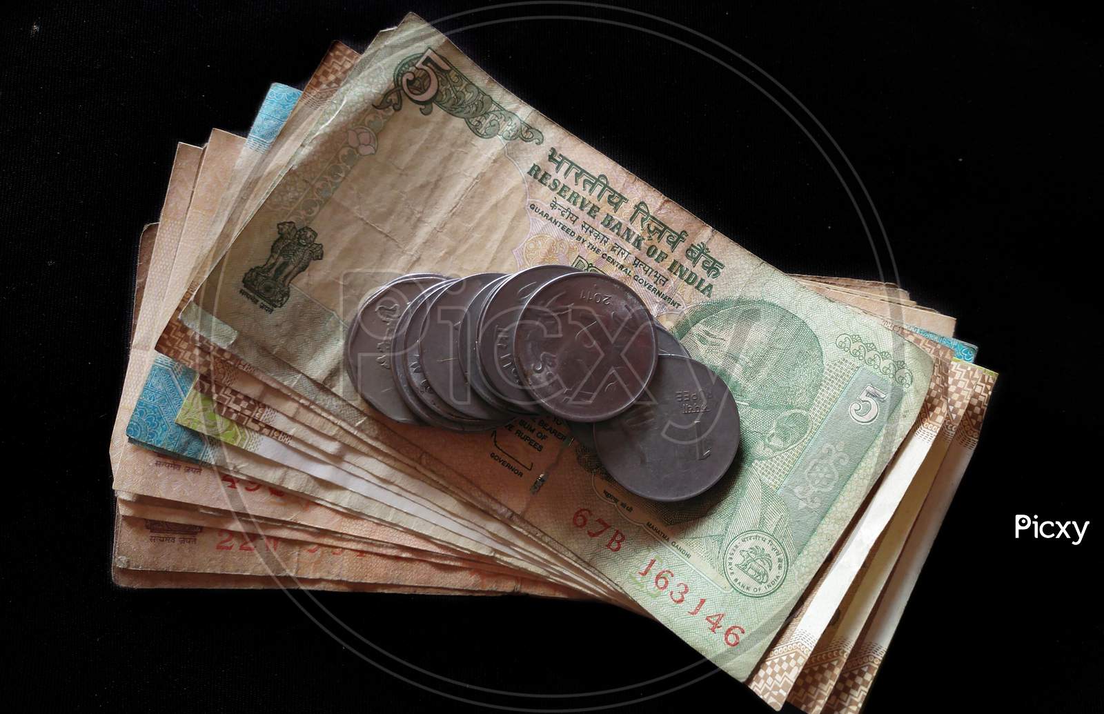 Indian paper currency with coins on isolated black background, concept of savings and investment