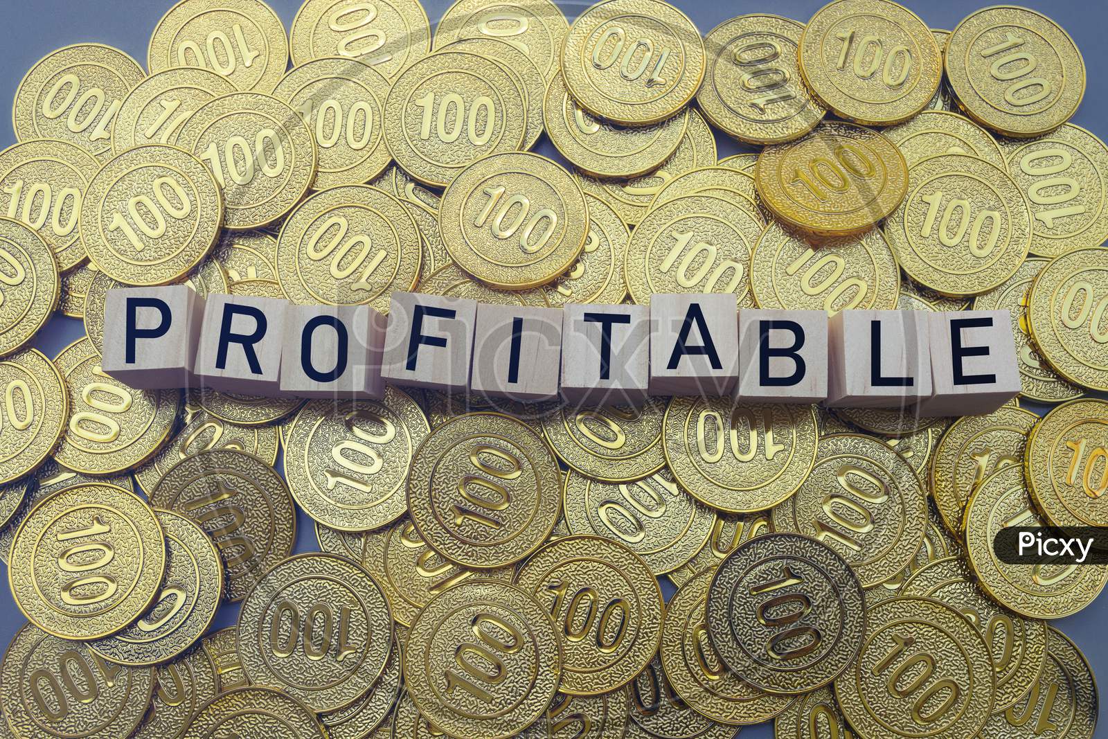 Profitable Text On Wood Block With A Pile Of Coins