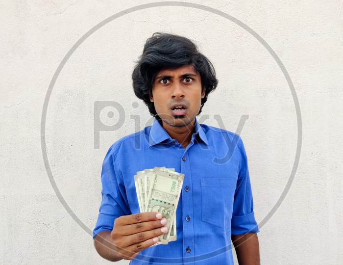 Shocking Young Handsome Indian Man In Blue Shirt Holding Four 500 Rupees Notes. White Background