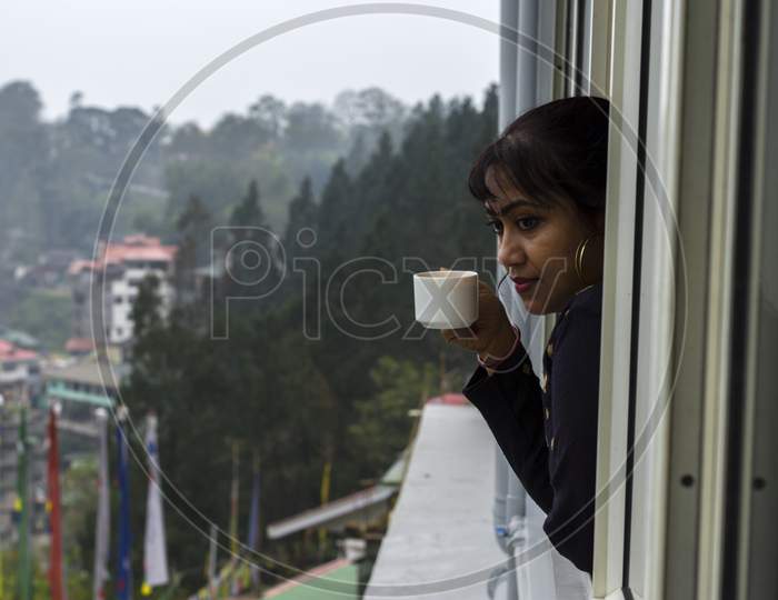 A Beautiful Female Traveller Injoying Cup Of Tea And Also Enjoying The View Of Gangtok City. Selective Focus.