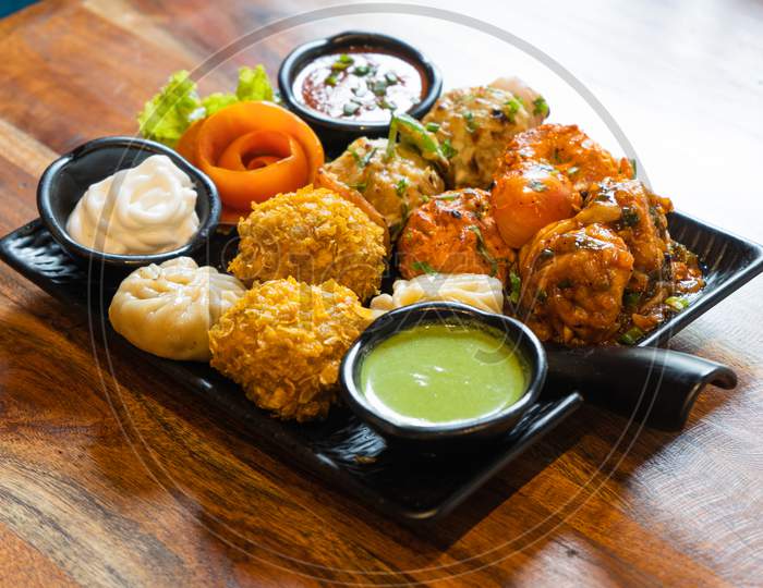 Tandoori Fried Roasted Momos Dimsum Pakora With Vegetable Flower Chicken And Green, White And Red Sauce Put In A Black Plate On A Wood Table