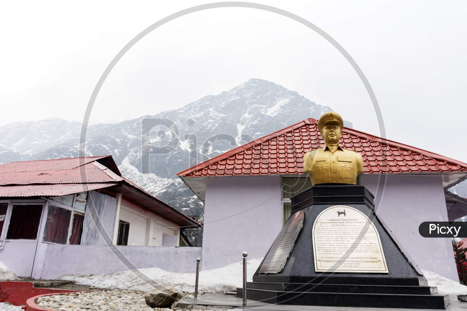 Statue Os A Soldier Near Baba Harbhajan Temple With Snow Covered Mountain In Background.