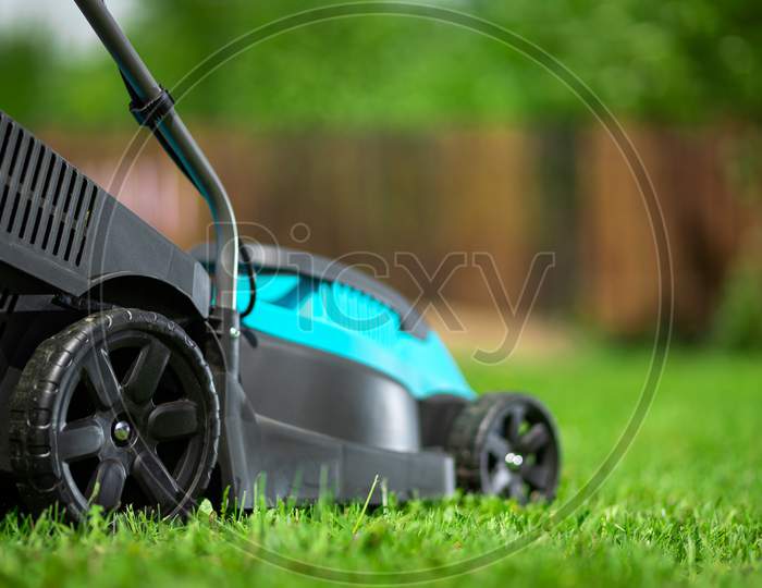 Close-Up Electric Lawn Mower, Mowing Grass, Lawn, Paths. Gardener Trimming The Garden.