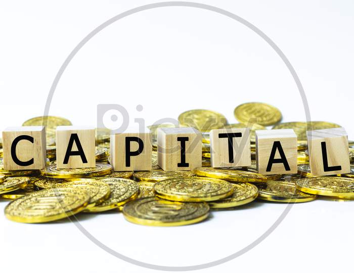 Capital Text On Wood Block With A Pile Of Coins
