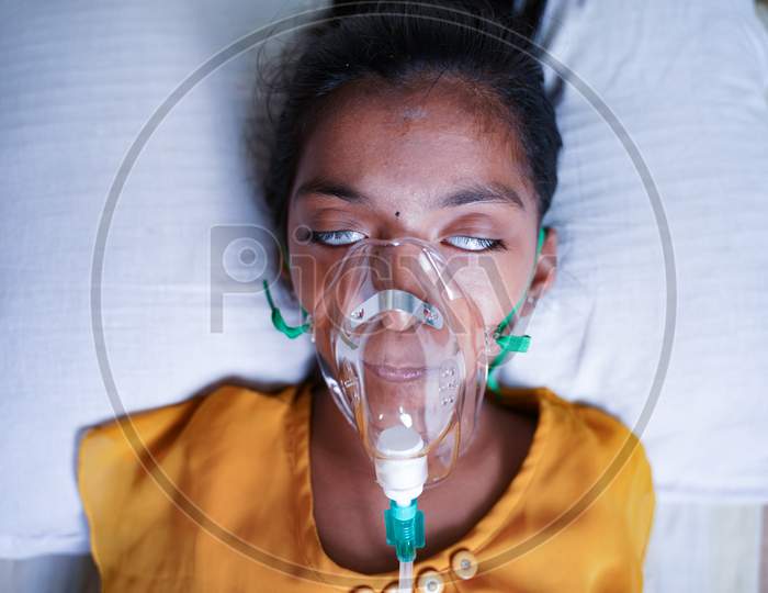 Close Up Top View Of Young Kid Breathing On Ventilator Oxygen Mask Due To Coronavirus Covid-19 Breathlessness Or Dyspnea - Concept Of Children Healthcare And Medical During Third Wave Pandemic.