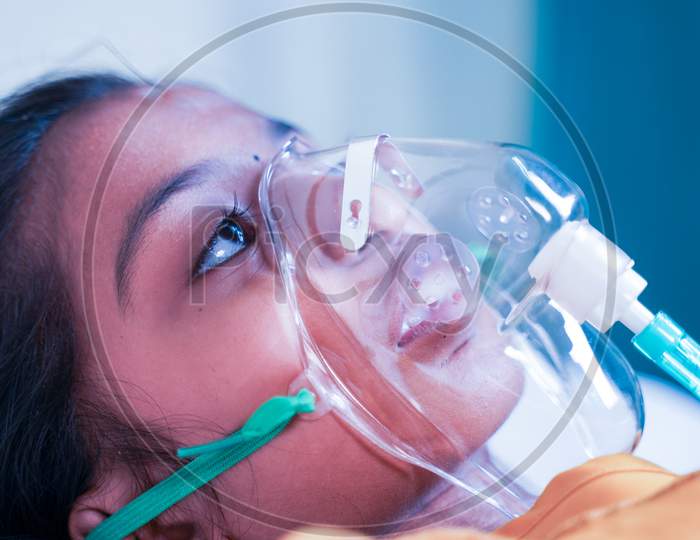 Close Up Shot Of Little Girl Kid Breathing On Ventilator Oxygen Mask At Hospital Due To Coronavirus Covid-19 Breath Shortness Or Dyspnea - Concept Of Children Healthcare And Medical During Pandemic.