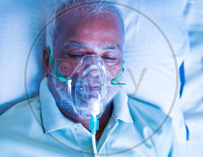 Close Up Top View Head Shot Of Old Breathing With Ventilator Oxygen Mask At Hospital Due To Coronavirus Covid-19 Breath Shortness Or Dyspnea