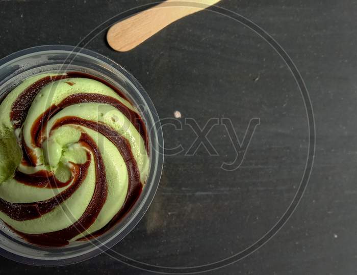 The Photo Is A Photo Of Avocado-Flavored Ice Cream In A Cup With A Black Background