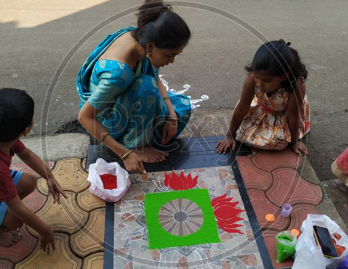 Women teaching rangoli art to kids