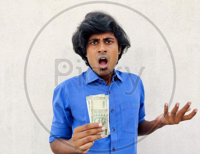 South Indian Young Man Feeling Extremely Shocked And Surprised Holding Two 500 Rupees Note. White Background