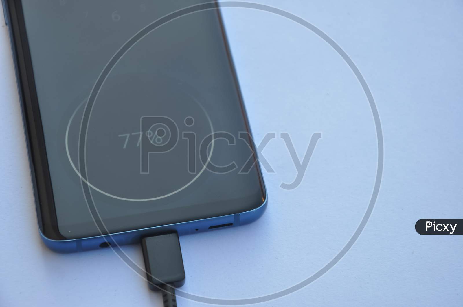 Overhead view of a smartphone connected with USB Type-C charging cable with negative space, Mobile phone charging - Stock Photo